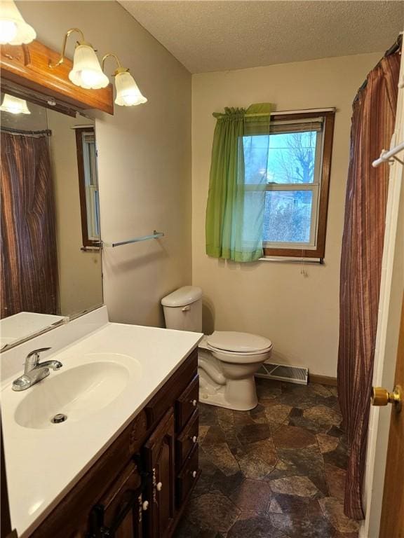 bathroom with vanity, toilet, and a textured ceiling