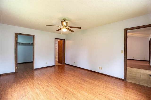 2008 Arthur Ave, Charleston, IL 61920 - unfurnished bedroom featuring light wood-style floors, a walk in closet, a textured ceiling, a closet, and ceiling fan