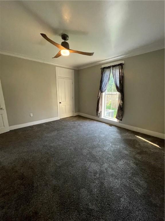510 S 5th St, Marshall, IL 62441 - spare room featuring ornamental molding, a ceiling fan, and dark colored carpet