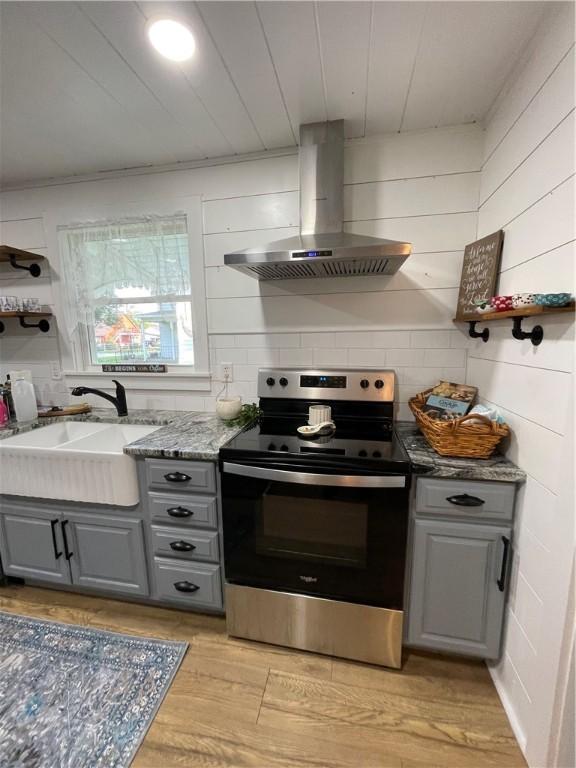 510 S 5th St, Marshall, IL 62441 - kitchen with stainless steel electric range, gray cabinetry, wall chimney range hood, light wood finished floors, and light stone countertops