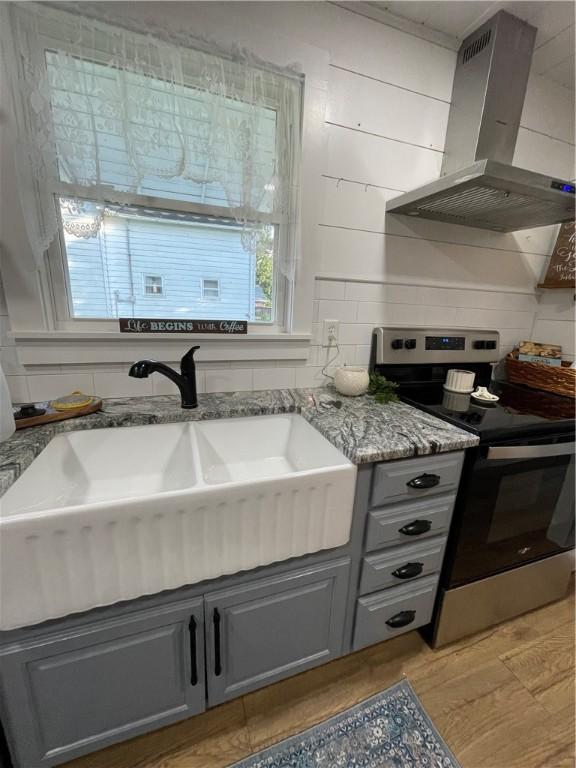 510 S 5th St, Marshall, IL 62441 - kitchen with electric range, island exhaust hood, gray cabinets, light stone countertops, and light wood-type flooring