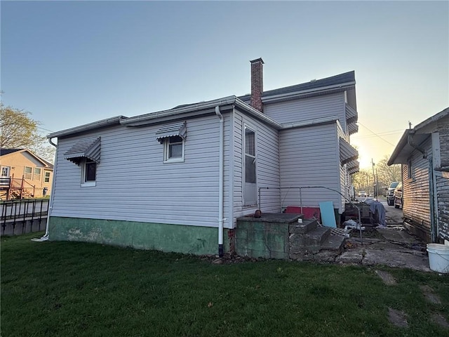 back of house with a lawn and a chimney