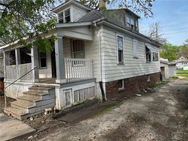view of property exterior featuring a chimney and a porch