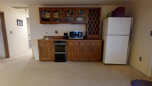 kitchen featuring white refrigerator, sink, and light carpet