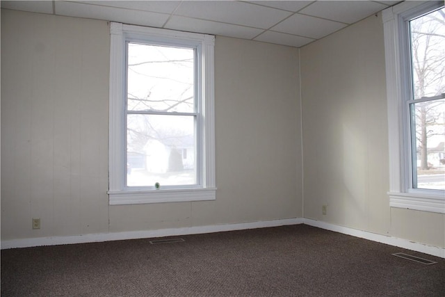 empty room featuring carpet floors, a paneled ceiling, and plenty of natural light