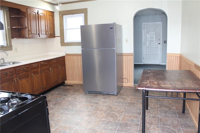 kitchen featuring stainless steel fridge, sink, and black gas range oven