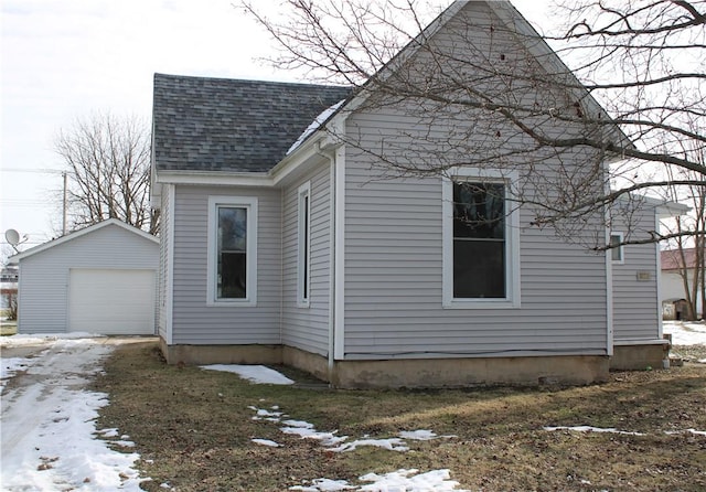 view of snowy exterior featuring a garage and an outbuilding