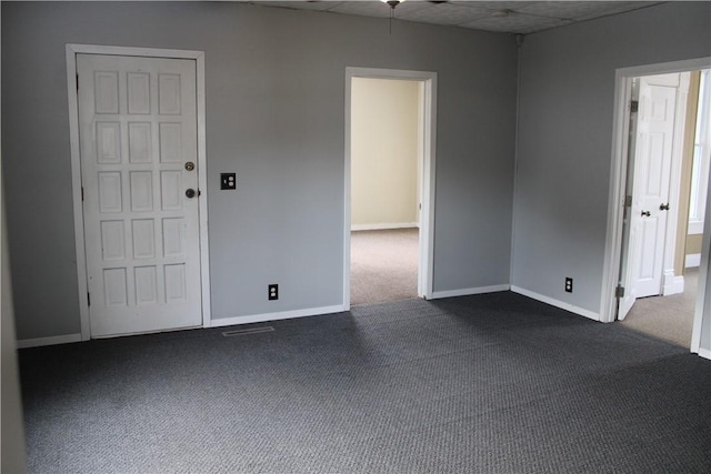 empty room featuring a paneled ceiling and dark carpet