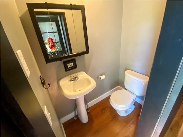 401 E Fourth St, Pana, IL 62557 - half bath featuring baseboards, wood finished floors, and toilet