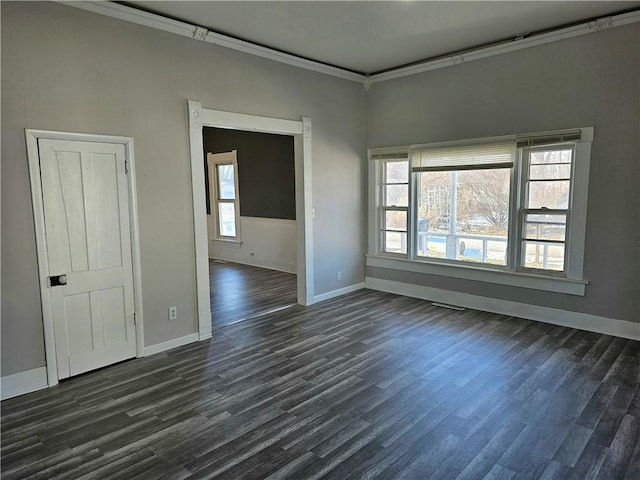 spare room featuring dark wood-type flooring, a wealth of natural light, and ornamental molding