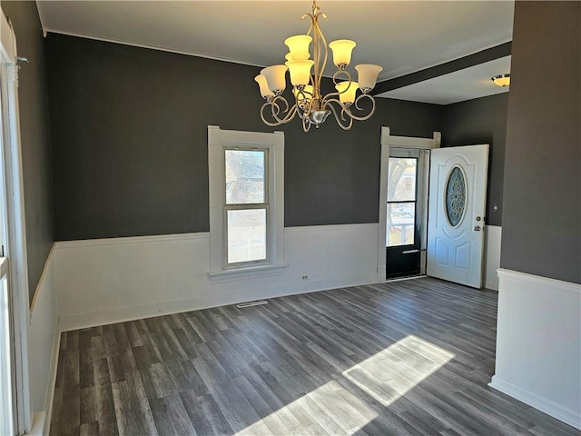 interior space with a wealth of natural light, a wainscoted wall, wood finished floors, and a chandelier