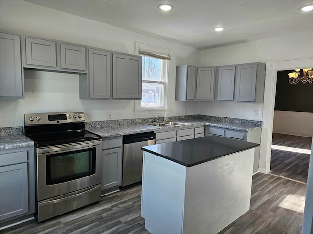 kitchen with appliances with stainless steel finishes, sink, gray cabinetry, dark hardwood / wood-style floors, and a kitchen island