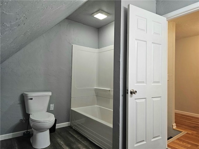 full bathroom with baseboards, toilet, wood finished floors, and a textured wall