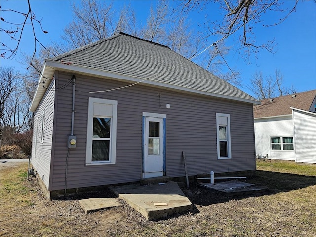 rear view of house with a yard and a shingled roof