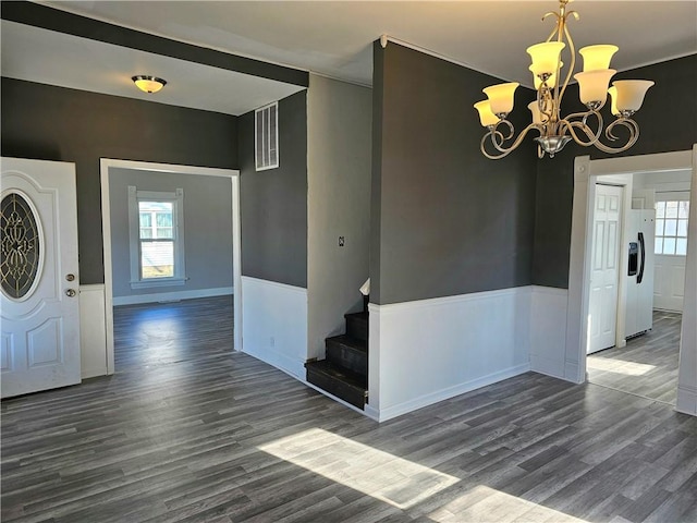 foyer entrance with a healthy amount of sunlight, wood finished floors, visible vents, and wainscoting