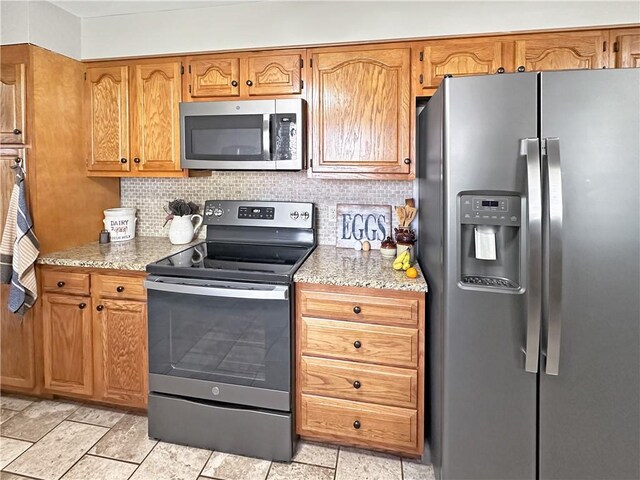 kitchen with appliances with stainless steel finishes, decorative backsplash, light stone countertops, and brown cabinetry
