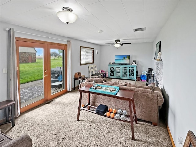 living area with carpet floors, a ceiling fan, french doors, and a fireplace