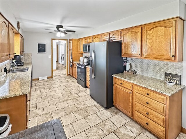 kitchen featuring a sink, stainless steel appliances, a ceiling fan, decorative backsplash, and baseboards