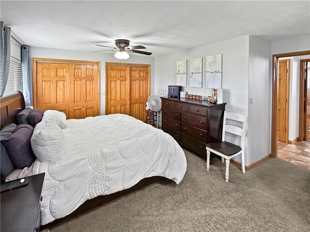 carpeted bedroom featuring two closets, a ceiling fan, and baseboards