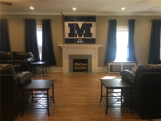 living room with radiator, a fireplace, ornamental molding, and hardwood / wood-style flooring