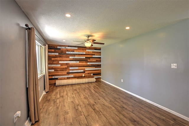 interior space featuring ceiling fan, wood walls, wood-type flooring, and a textured ceiling