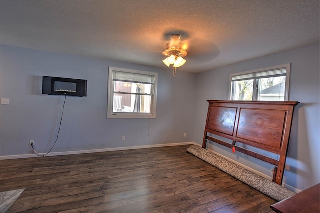 empty room featuring plenty of natural light, ceiling fan, dark hardwood / wood-style flooring, and a textured ceiling