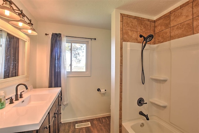 bathroom featuring hardwood / wood-style floors, vanity, shower / bathtub combination with curtain, and a textured ceiling