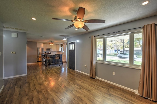 living room featuring ceiling fan, dark hardwood / wood-style flooring, and a textured ceiling