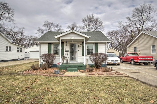 bungalow with a detached garage, an outbuilding, roof with shingles, and a front yard