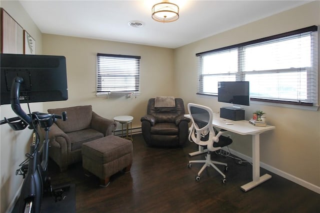 office space with baseboard heating, wood finished floors, visible vents, and baseboards