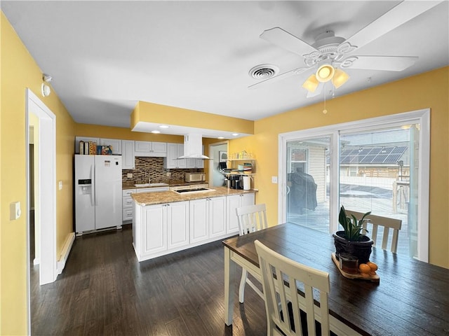 kitchen with visible vents, decorative backsplash, white appliances, a peninsula, and extractor fan