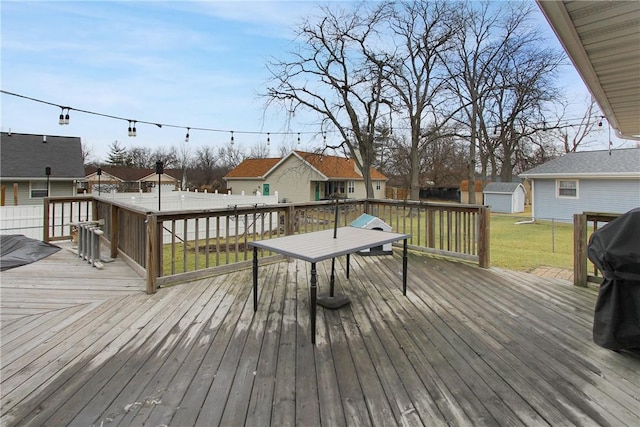 wooden deck featuring an outbuilding, a yard, a storage unit, and a residential view