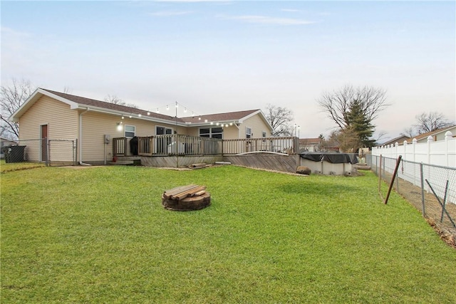 view of yard featuring a fire pit, a fenced backyard, a wooden deck, and a fenced in pool