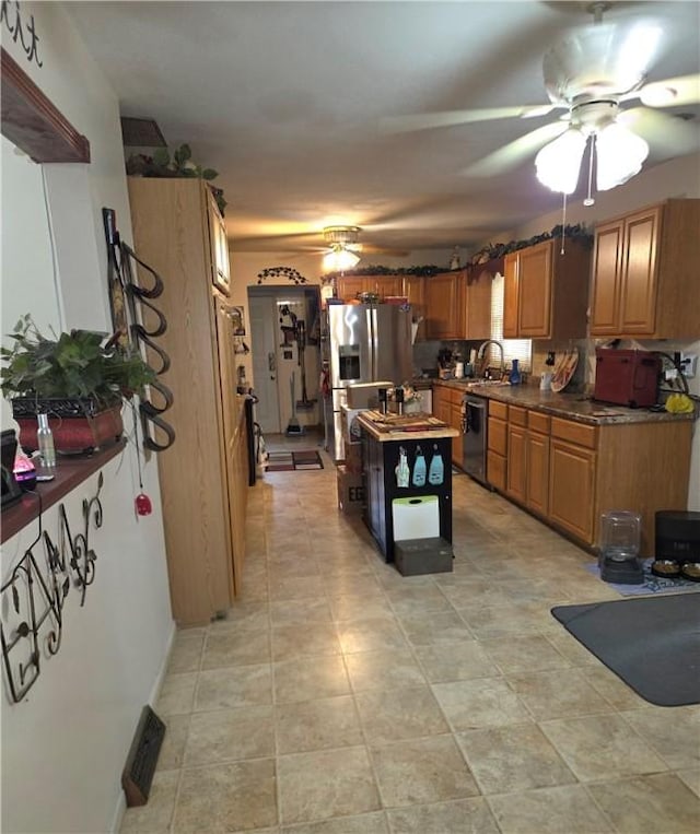 3254 Vista Dr, Danville, IL 61832 - kitchen featuring ceiling fan, appliances with stainless steel finishes, a kitchen island, and brown cabinetry