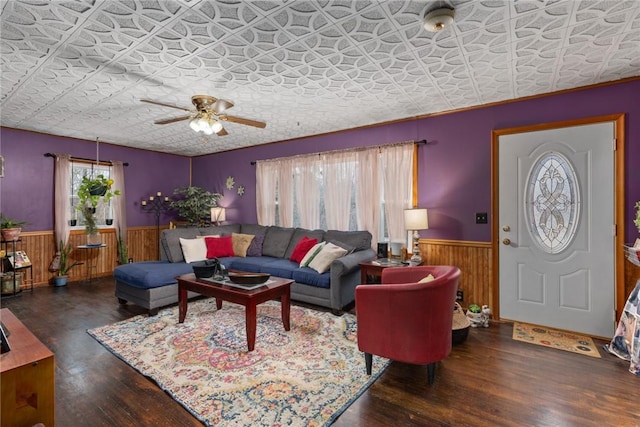 living room with dark wood-type flooring, wooden walls, and ceiling fan