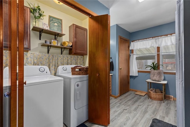 laundry room with cabinets, washing machine and dryer, and light hardwood / wood-style floors