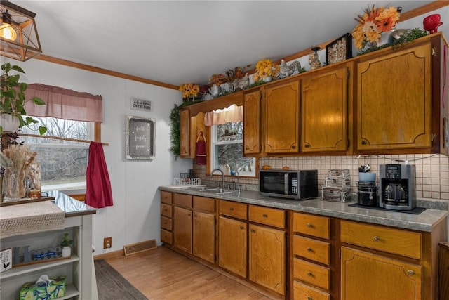 kitchen with crown molding, sink, light hardwood / wood-style flooring, and decorative backsplash