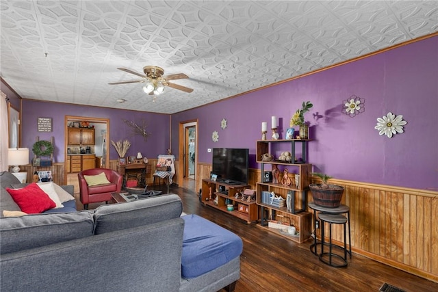 living room featuring dark hardwood / wood-style floors, wooden walls, and ceiling fan