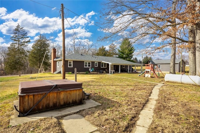 view of yard with a hot tub and a playground