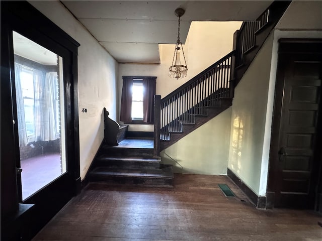 stairway with hardwood / wood-style flooring, an inviting chandelier, and a wealth of natural light