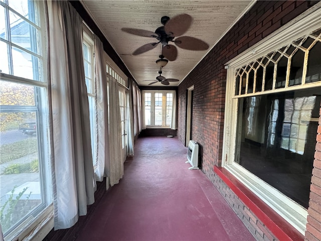 unfurnished sunroom with ceiling fan and an AC wall unit