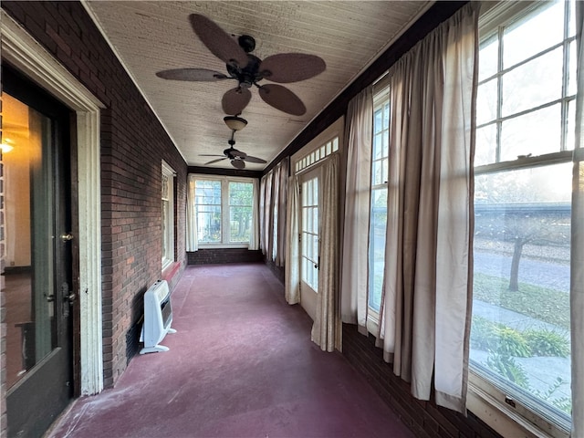 unfurnished sunroom with ceiling fan and an AC wall unit