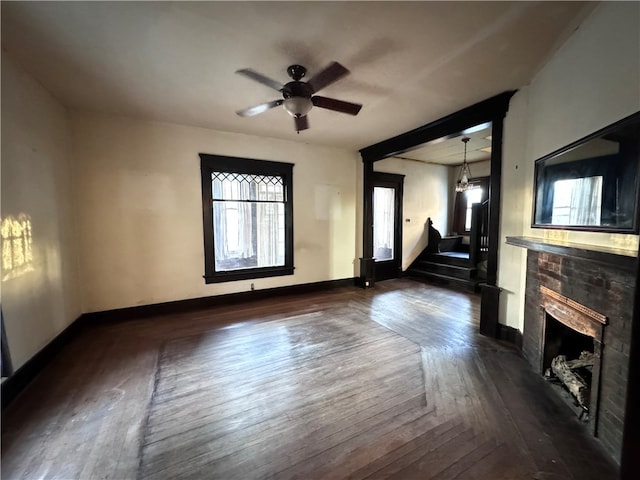 unfurnished living room with ceiling fan, a fireplace, and dark wood-type flooring