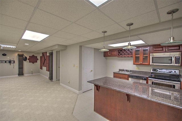 kitchen with stainless steel appliances, a sink, baseboards, a paneled ceiling, and a breakfast bar area