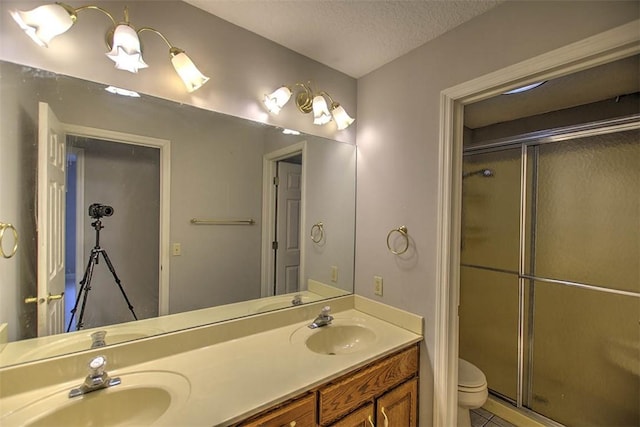 bathroom featuring double vanity, toilet, a stall shower, and a sink
