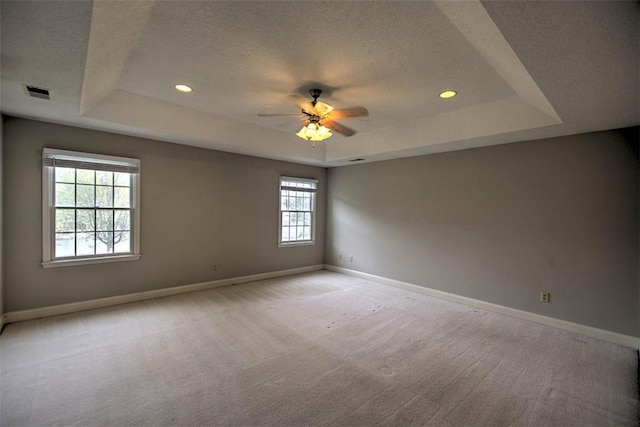 spare room featuring baseboards, a textured ceiling, and a raised ceiling
