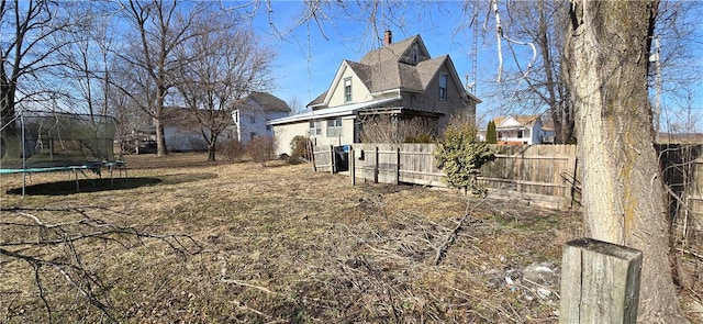 view of home's exterior with a trampoline and fence