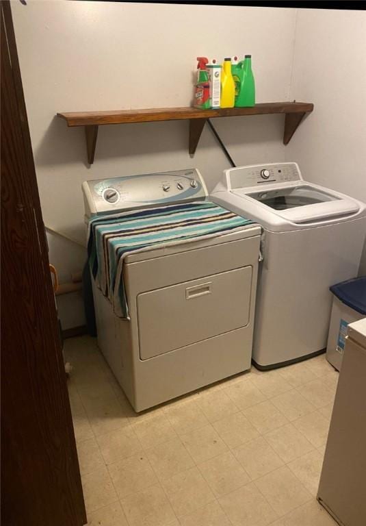 clothes washing area featuring laundry area, light floors, and washing machine and clothes dryer