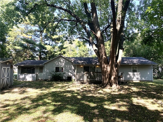 back of property with a lawn and a storage unit