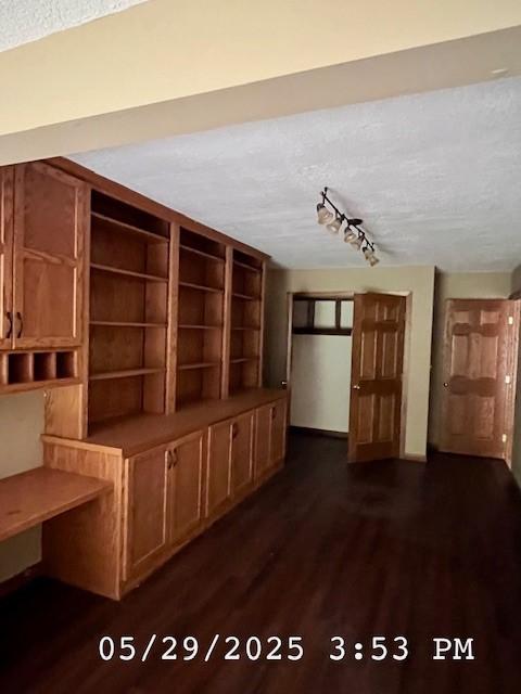 6680 John Dr, Mt Zion, IL 62549 - unfurnished living room featuring a textured ceiling, dark wood-style floors, and rail lighting